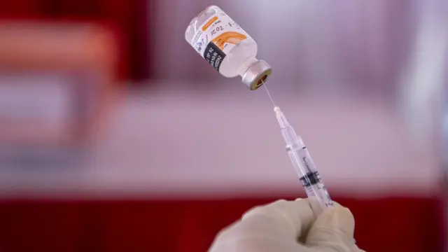 Petugas kesehatan memasukan vaksin COVID-19 ke jarum untuk disuntikkan, vaksin.