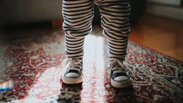 beba stoji na nogama u patikama