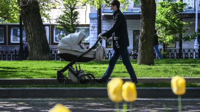 Un hombre lleva a un bebé en un cochecito.