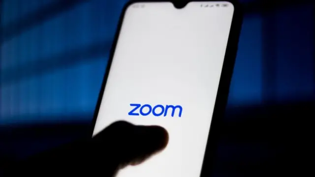Zoom Meetings logo is seen displayed on a smartphone
