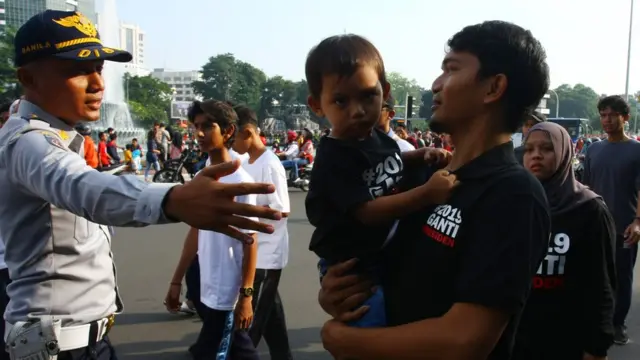Petugas menghalau warga yang menggunakan atribut bernuansa politik memasuki arena Car Free Day arena tidak sesuai dengan Pergub No.12 tentang larangan melakukan kegiatan politik diacara dan tempat berlangsungnya Hari Bebas Kendaraan Bermotor atau Car Free Day (CFD) di Jakarta, Minggu (6/5).