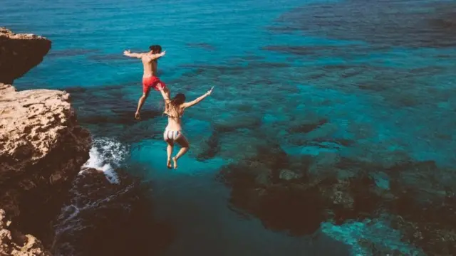 Casal pulando de pedra