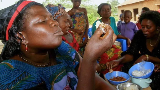 Women eating Kenkey a staple dish made from maize in Ghana, West Africa.