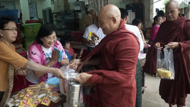 Personas donan comida a monjes budistas en Birmania
