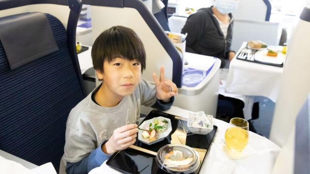 Criança comendo refeição em primeira classe de avião parado da ANA