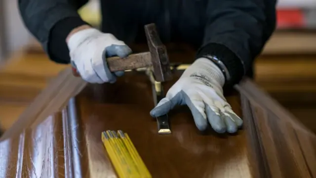 Homem trabalha com martelocentral de apostas netum caixão.