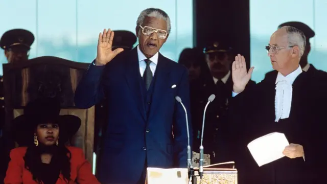 Nelson Mandela lève la main pour prêter serment lors de son investiture en tant que président de l'Afrique du Sud.