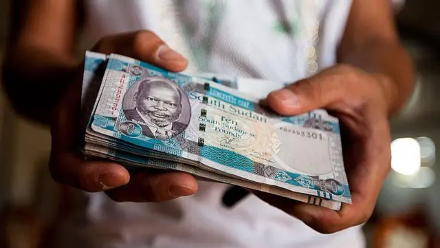 Un homme tenant de la monnaie soudanaise.