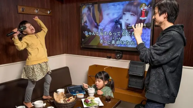 Pai cantando em karaokê com as filhas