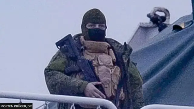 ఓడపై రైఫిల్తో నిల్చున్న వ్యక్తి