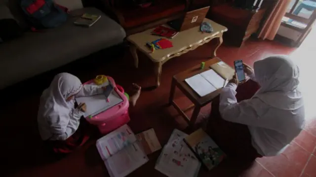 Siswa menggunakan ponsel untuk mengerjakan tugas sekolah yang diberikan oleh guru mereka saat pemerintah menerapkan sistem pembelajaran online di tengah pandemi virus corona di Jakarta, Indonesia pada 21 Juli 2020.