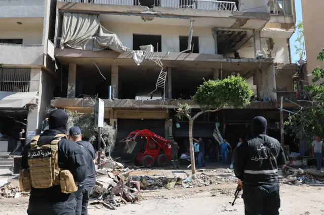 Lübnan güvenlik görevlileri, 14 Haziran 2026'da Beyrut'un güney banliyölerinde İsrail hava saldırısının hedef aldığı bir apartmanın yakınında duruyor.