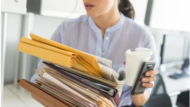 Mulher carregando documentosjogo de apostas cassinoescritório