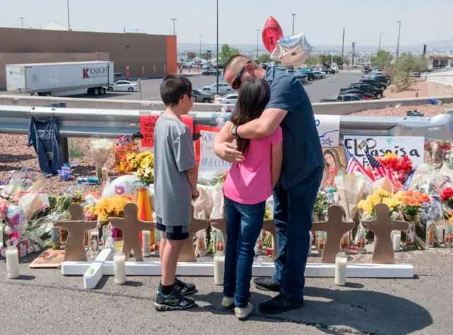 Un hombre y dos niños ante un altar por las víctimas de El Paso