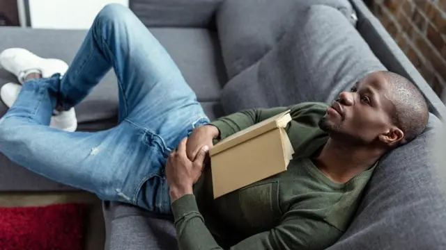 شاب يستلقي على أريكه وفي يده