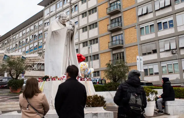 Pipo pray in front of di statue of Pope John Paul II outside Rome Gemelli Polyclinic, wia dem admit Pope Francis for hospital.