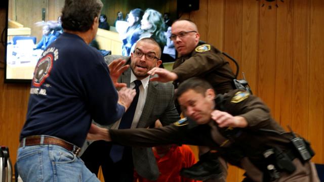 Court security staff try to shield Larry Nassar after the father of two of his victims lunged at him