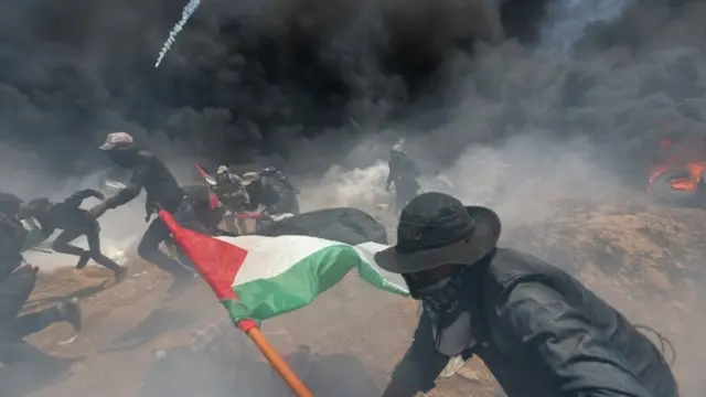 Palestinian demonstrators run for cover from Israeli fire and tear gas during a protest against US embassy move to Jerusalem and ahead of the 70th anniversary of Nakba, at the Israel-Gaza border in the southern Gaza Strip 14 May 2018