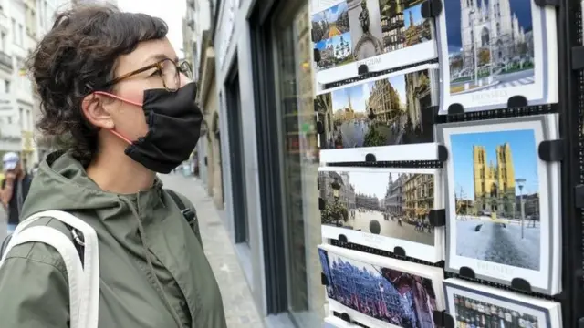 Mulher observa cartões postais na Bélgica