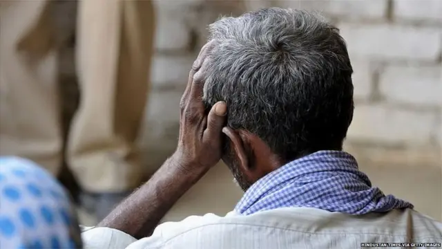 सिर पर हाथ रखकर बैठा व्यक्ति