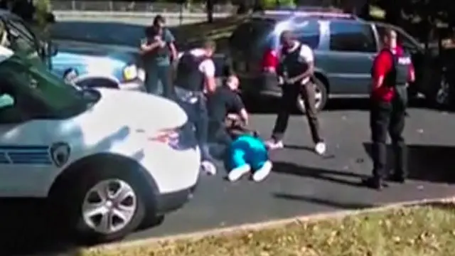 Agentes rodean a Scott, quien yace en el suelo