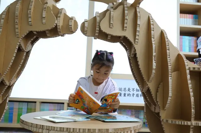Seorang anak perempuan tengah membaca buku di China. 