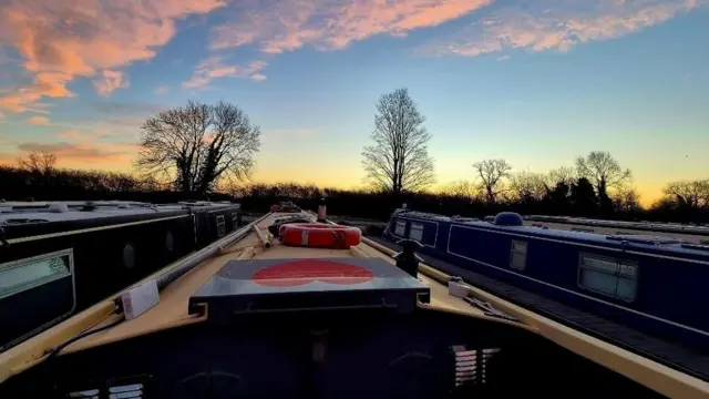 Barcos del canal de Banbury, Oxfordshire alineados uno al lado del otro mientras sale el sol en una mañana helada.