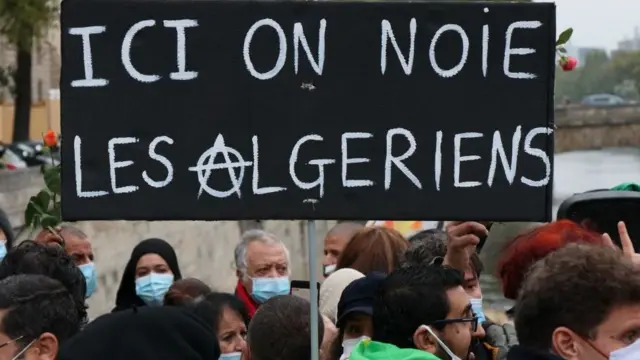 Placard disant : "Ici nous noyons les Algériens" vue lors d'une cérémonie de commémoration du 59e anniversaire du massacre de Paris en 1961 au pont Saint-Michel sur la Seine à Paris, France - 17 octobre 2020.