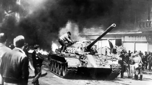 Чехословацкий подросток забирается на советский танк T-54 около здания пражской радиостанции. 21 августа 1968 года