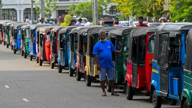 Des conducteurs de pousse-pousse font la queue dans une rue pour acheter de l'essence à la station-service de la Ceylon Petroleum Corporation à Colombo