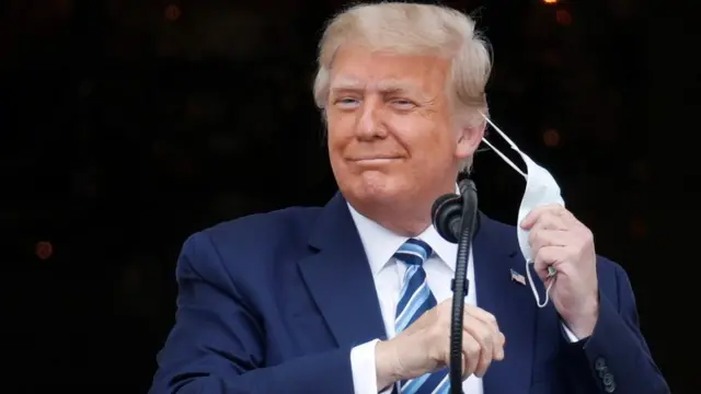 U.S. President Donald Trump takes off his face mask as he comes out on a White House balcony to speak to supporters gathered on the South Lawn for a campaign rally that the White House is calling a "peaceful protest" in Washington, U.S., October 10, 2020.