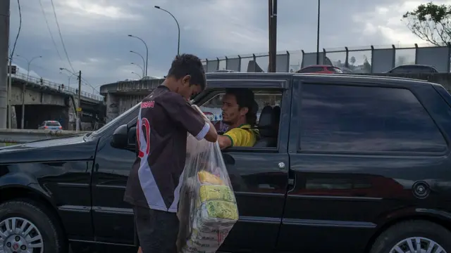 Menino vendendo biscoitokaizen gaming betanopolvilho para motorista parado no trânsito