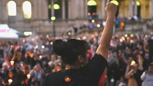 Una mujer levanta el puño frente a una muchedumbre durante una vigilia para Cassius Turvey