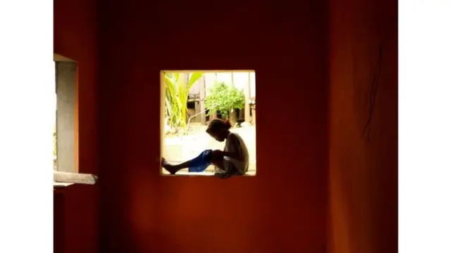 दीवार पर बैठी बच्ची