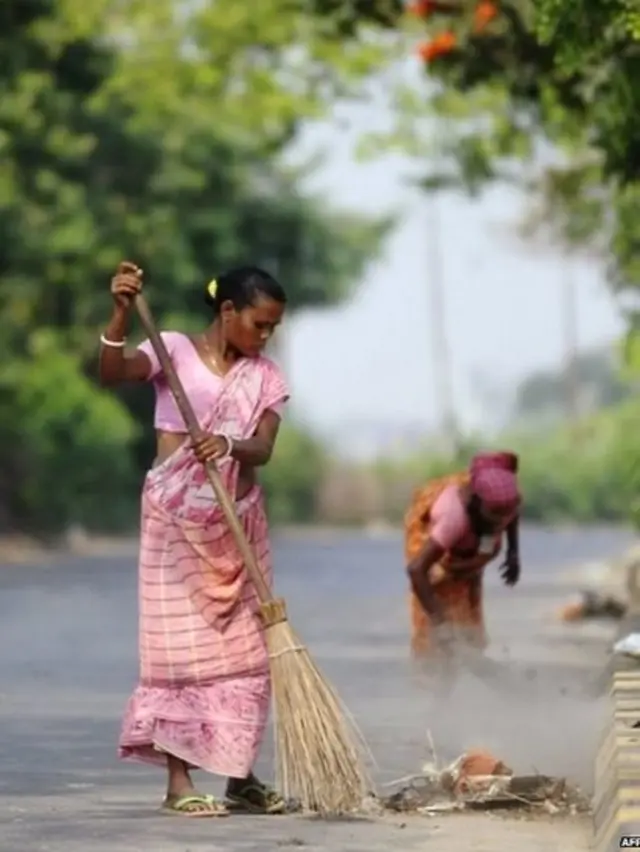 रस्ते झाडत असताना महिला.