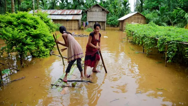 Girls row past submerged houses