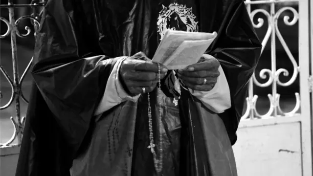 Manos del animero con camándula y libro de rezos.