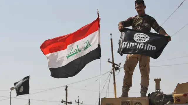 Iraqi soldier dey hold IS flag upside-down