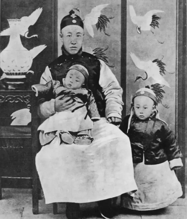 1909: Prince Chun, regent and controller of the nation, with his youngest son on his knees and Puyi (1906-1967), Emperor of China, at his side.