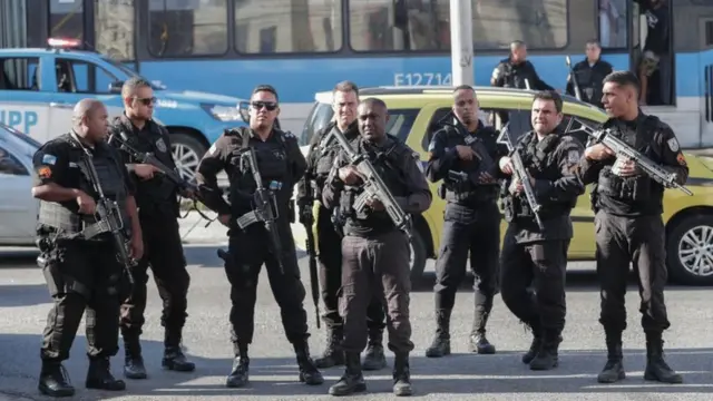 Policiais fortemente armados lado a lado na rua