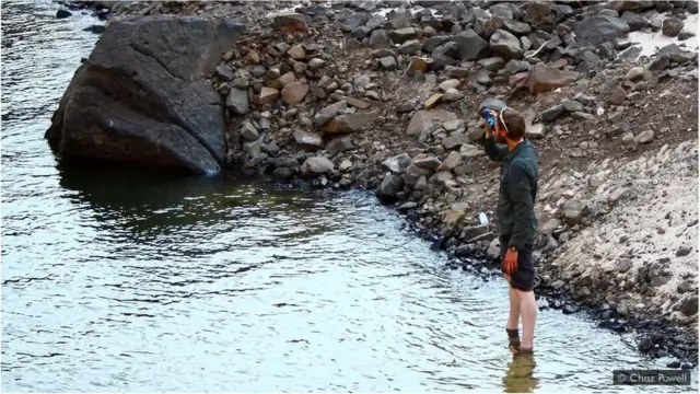 Chaz Powell boit de l'eau du fleuve Zambèze.