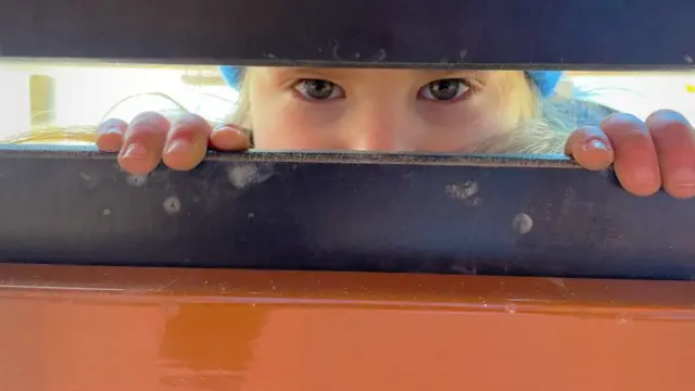 Ksusha mira por entre una puerta