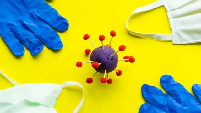 Covid-19, blue plastic gloves and face mask on a yellow background