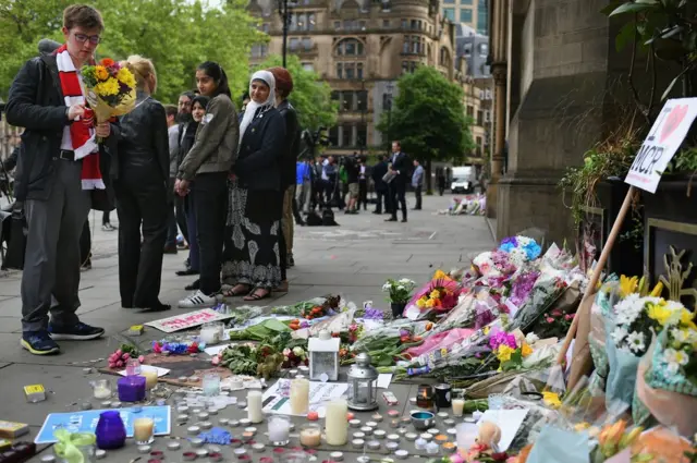 Manchester, 24 may 2017. Küçədən keçənlər gül dəstələri, yazılı ithaf və başsağlıqlarına nəzər yetirirlər