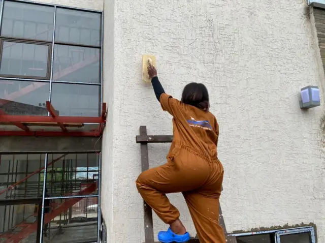 Herniette Nishimwe ari gutunganya urukuta bari gukoraho design