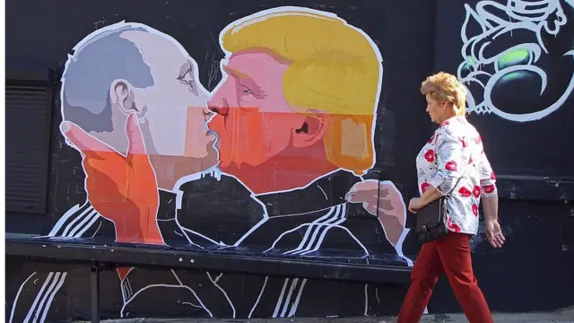 Плакат с целующимися Путиным и Трампом на улице Вильнюса