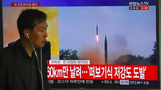 韓國首爾火車站內一名市民走過正在播報朝鮮試射導彈消息的電視屏幕（5/4/2015）