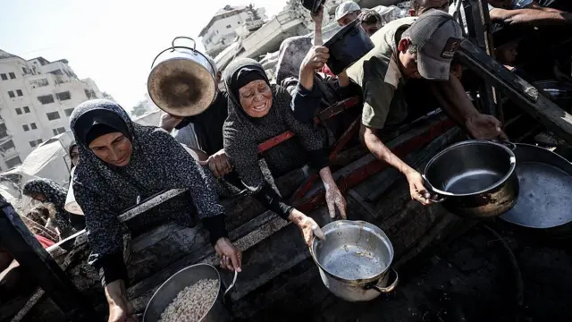 زنان و کودکان در صف دریافت کمک‌های غذایی در نوار غزه