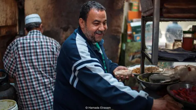 阿米尔在埃及开罗经营着一辆餐车，他在准备沙拉三明治时，灰白的胡须下露出了微笑。