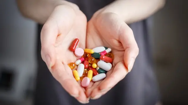 Manos de mujer mostrando pastillas.